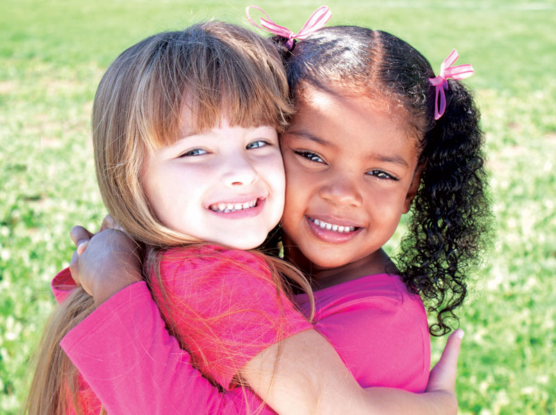 Two young girls hugging and smiling.